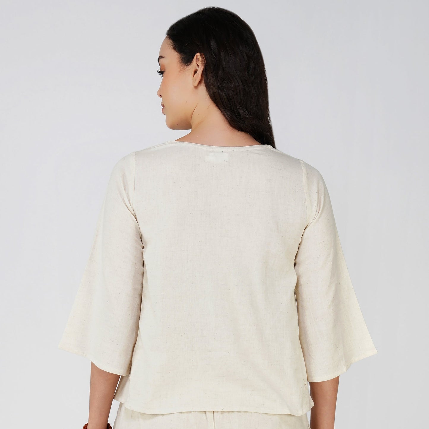 Woman wearing a cream-colored outfit on a white background